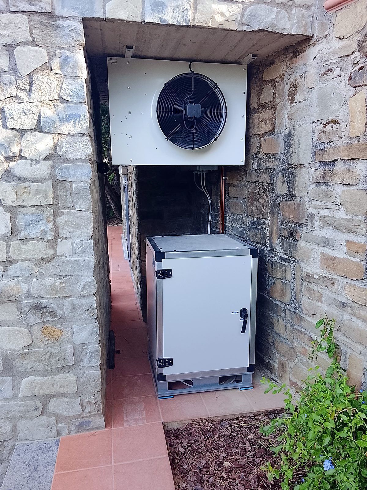 Unità esterna e condensatore installati contro il muro in pietra